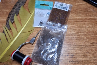 Použitý materiál: háčik Hends 144 veľkosť 14, čierna viazacia nitka, tmavomedená hlavička 3,3 mm typu jig off, zlatý drôtik, pierko z bažanta, farbené pierko zo sliepky, spectra UV bronz dabing, olovený drôtik 0,4 mm.