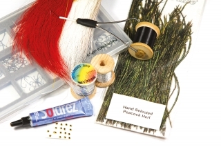 Materiály:
Strímrový háčik, čierna viazacia niť, strieborná lametka, strieborná niť, biela srsť „Bucktail“, červená srsť „Bucktail“, pierka z páva, umelé oči, UV lak.