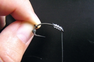 1. Fluorocarbon naviažeme na háčik klasickým bezuzlovým spôsobom. Na ramienko háčika navlečieme kovovú slzičku a gumenú zarážku.